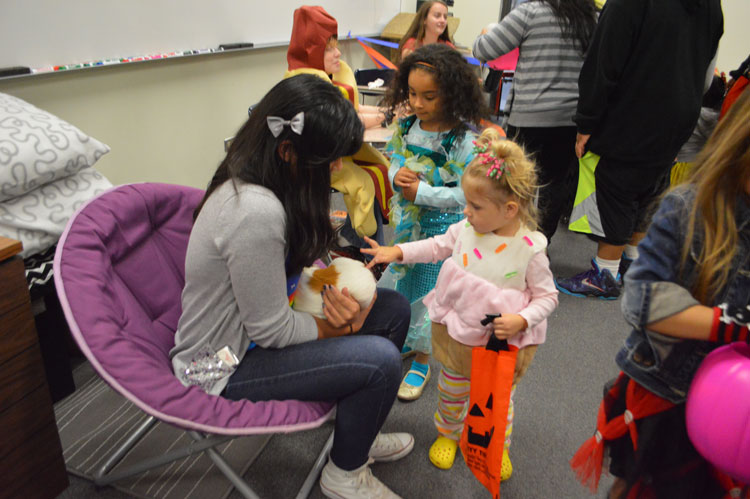 Students from the Speech Team hold animals, like guinea pigs, for young trick-or-treaters at the Halloween night.