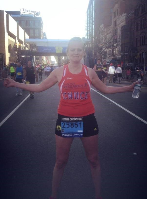 Kim Grauer at the finish line of the Boston marathon with her dads name on her jersey.