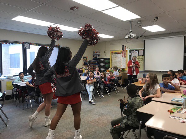 Basketball players and cheerleaders visit the local elementary school and read to them.