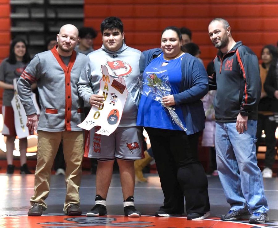 Mando Hernandez stands with his coaches and family at Seniors Night.