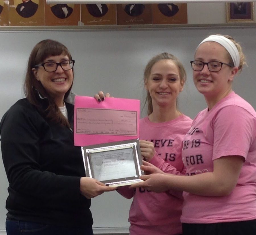 Three pink-out supporters holding up a check for $3,000 to be donated to research into cures for breast cancer 