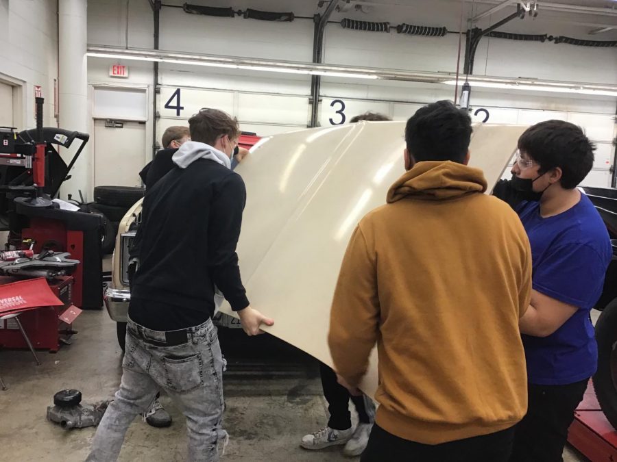 Students in the automotive tech class work to re-attach a hood.