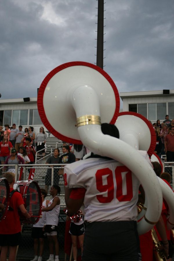 A PHS football player plays the tuba as the marching band walks into the stadium. The player had just ran from the junior varsity game to  perform.