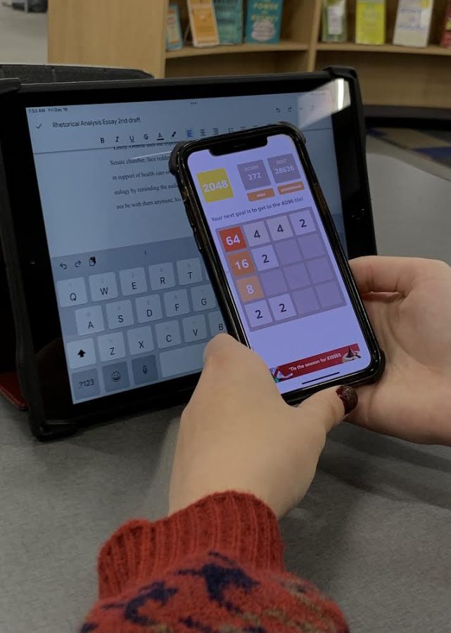 A+student+plays+a+mobile+game+instead+of+working+on+class+work.
