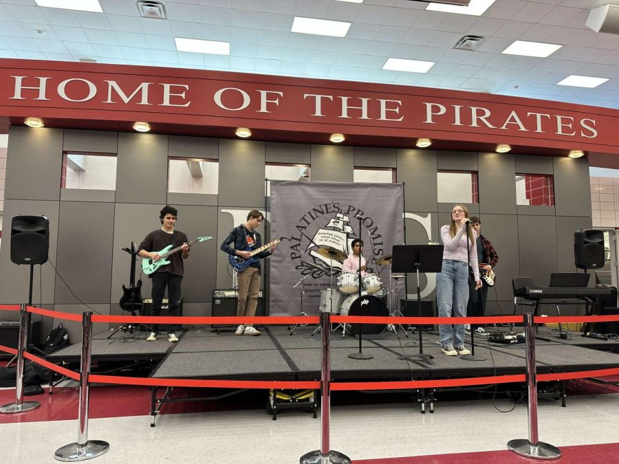 Seniors Alex Panayotov, Matt Stepp, Sarvesh Satish, Will Kryiazakos, and Maddy Hake perform Kilby Girl by the Backseat Lovers to begin the event. Their band is named Plastic Jackets.