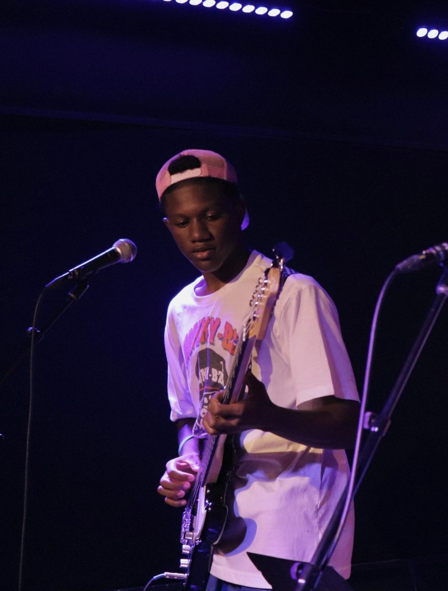 Sophomore Q’uran Clark plays guitar in front of packed stage at Madcats.