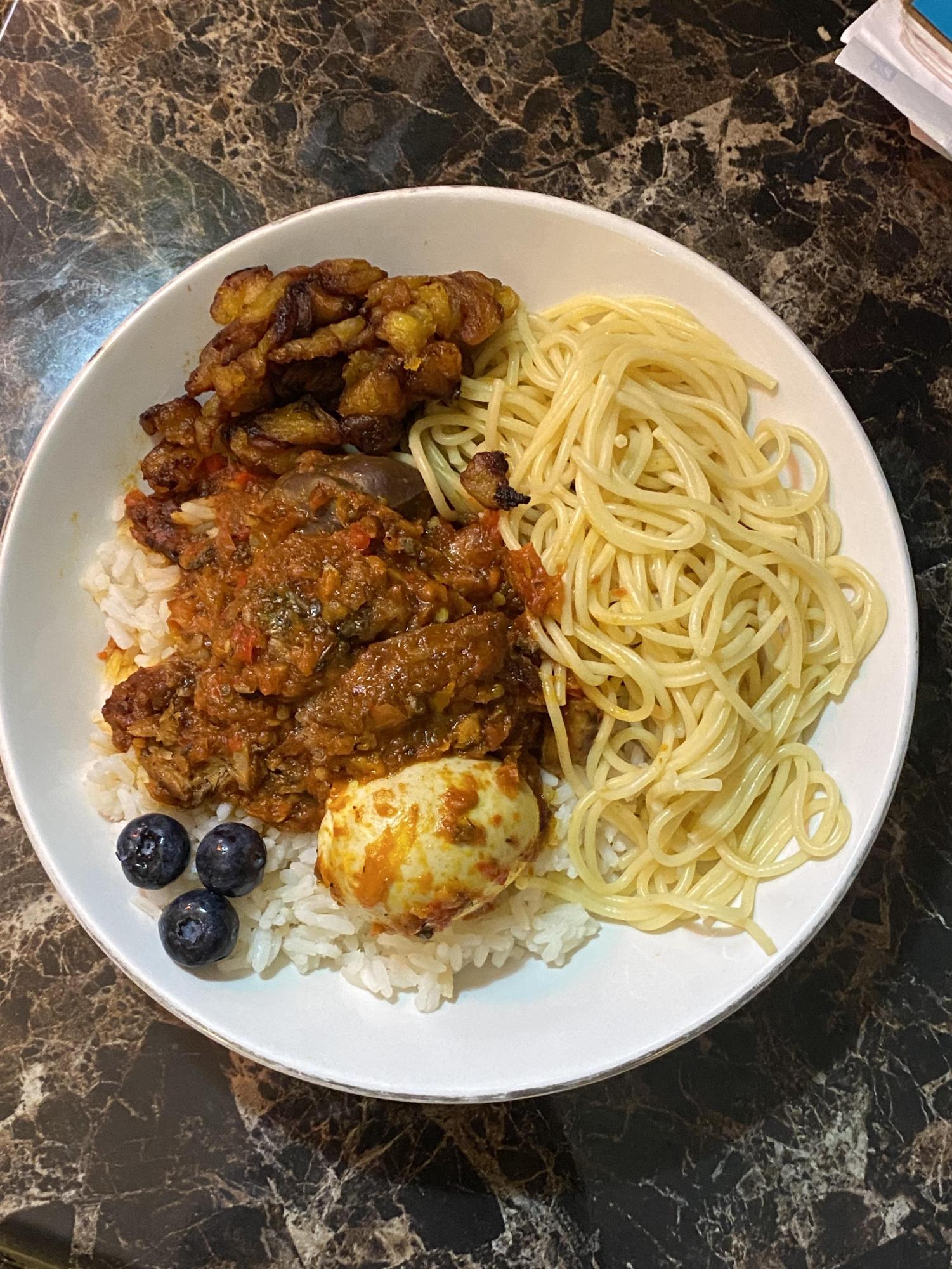 Spaghetti topped with fried Nigerian pepper and fried plantain on the side 