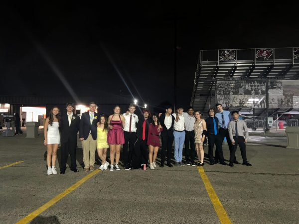 A group of students line up for a photo in front of the stadium where the homecoming dance was taking place.