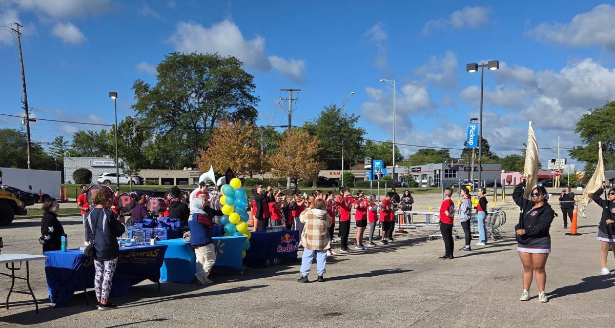Palatine High School students from band and color guard perform in the parking lot of the Walmart on Rand Rd. 