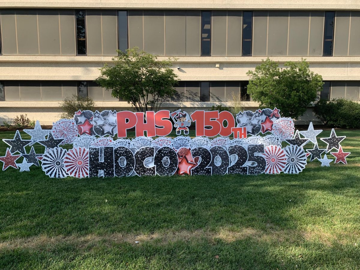 In front of the Palatine High School main entrance a sign sits in the grass. In big bright letter its displays "PHS 150th HOCO 2025".