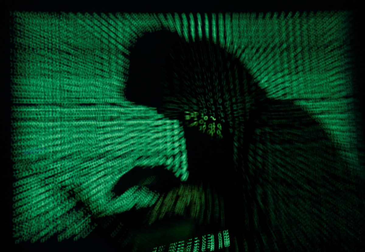 A hooded man holds a laptop computer as cyber code is projected on him in this illustration picture taken on May 13, 2017. REUTERS/Kacper Pempel/Illustration