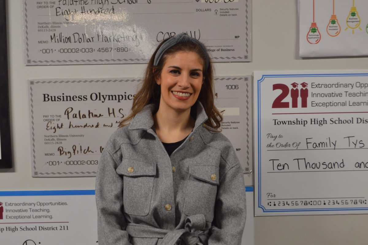 Adrienne Stewart stands outside the Palatine High School business department, where displays of student-earned competition checks highlight the impact of hands-on learning and entrepreneurship in her classes.

