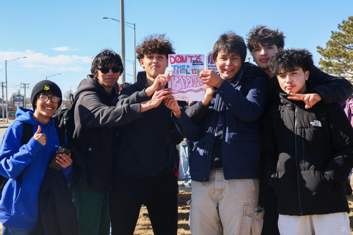Six students hold a sign protesting ICE deportations during the walkout.