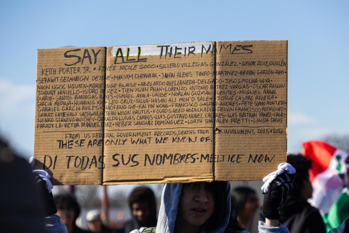 A student holds a sign listing names of individuals who have died following encounters involving ICE.