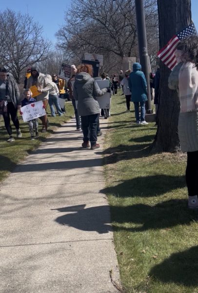 Protestors standing and walking around with signage to share their thoughts on the current administration.
