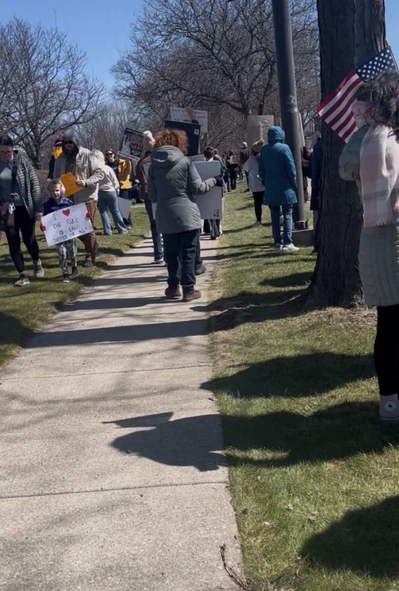 Protestors standing and walking around with signage to share their thoughts on the current administration.